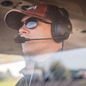 Person wearing a helmet and sunglasses inside a vehicle